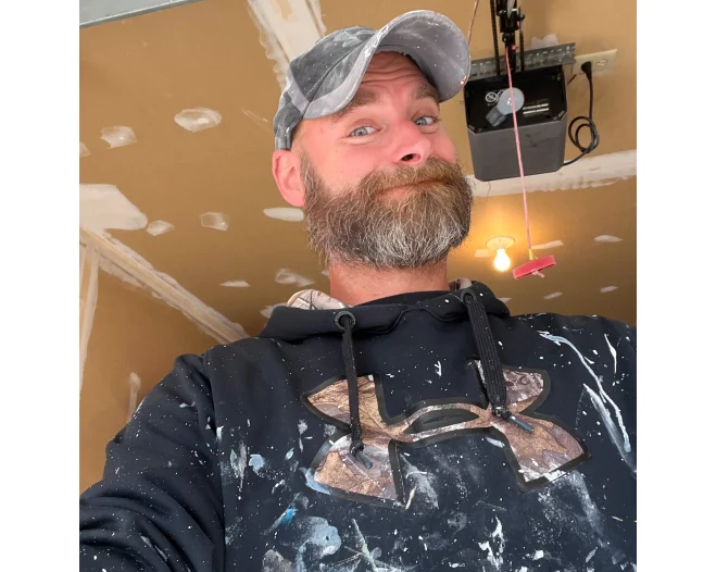smiling man and wearing cap and hoodie with paint
